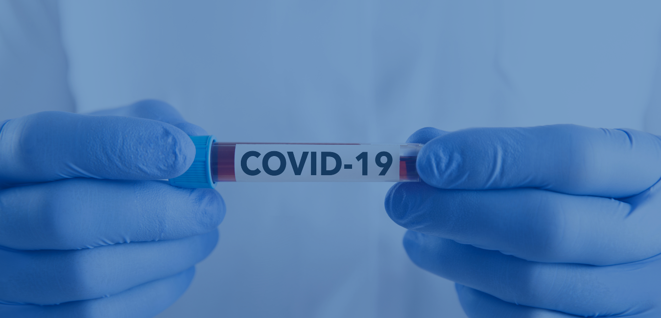 Person wearing blue gloves holding a tube labeled COVID-19 - header image for covid testing page