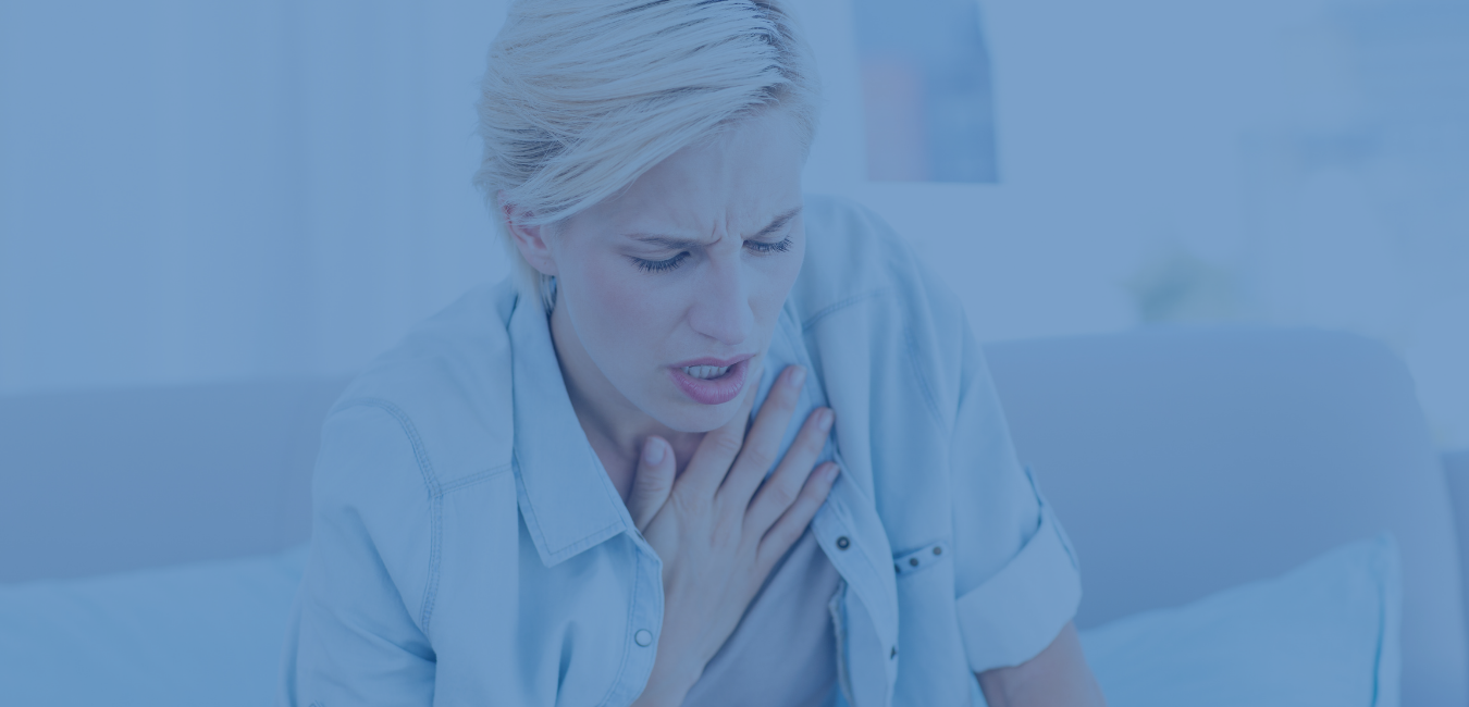 woman in blue shirt over gray tank top holding chest - photo header for difficulty breathing page at university urgent care