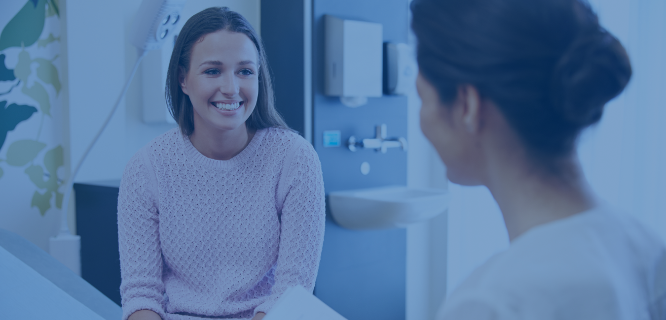 Female patient in pink sweater talking to a women doctor. Header image for std testing page